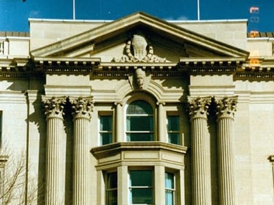 Ornate Beaux Arts building facade with columns, pediment, and arched entrance viewed from the street.
